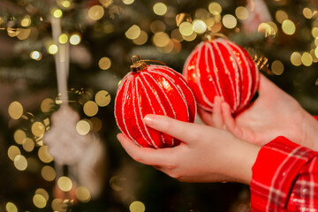 Christmas tree Toy. Christmas tree with red shiny balls.child in plaid pajamas takes red Christmas balls 