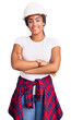 © Krakenimages.com - Young african american woman with braids wearing hardhat and builder clothes happy face smiling with crossed arms looking at the camera. positive person.