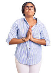 Wall Mural - Young african american woman with braids wearing casual clothes and glasses begging and praying with hands together with hope expression on face very emotional and worried. begging.