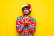 pensive young indian man in new year clothes thinks and plans over yellow isolated background