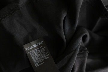 Sticker - Clothing label in different languages on black garment, closeup