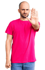 Sticker - Young handsome man wearing casual t shirt doing stop sing with palm of the hand. warning expression with negative and serious gesture on the face.