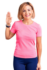 Poster - Young blonde woman wearing sportswear waiving saying hello happy and smiling, friendly welcome gesture