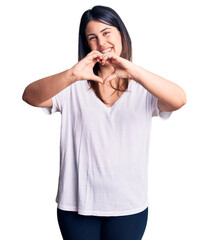 Sticker - Young beautiful brunette woman wearing casual t-shirt smiling in love doing heart symbol shape with hands. romantic concept.