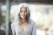 Happy and confident mature woman exuding elegance and positive energy, showing off the beauty of natural gray hair.