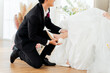 © twinsterphoto - A devoted groom helps his bride with footwear, a gentle gesture of love and support