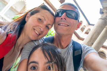 Poster - A family of two adults and their daughter taking selfies in the Real Alcazar of Sevilla