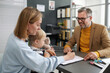 © Mediaphotos - Young woman sitting with her little son and filing documents for social benefits