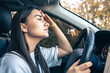 © puhimec - Tired young woman car driver suffering from headache migraine driving vehicle.