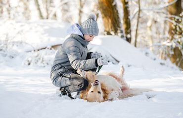 Wall Mural - Teenage Girl Plays With Golden Retriever In Snowy Forest, Sitting With Dog