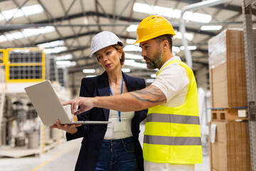 Wall Mural - Female manager talking with foreman, checking production plan on notebook. Woman quality controller checking quality of products, talking with technician.