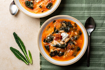 Wall Mural - Tuscan kale soup, homemade meal, with veggies, cabbage, carrot, tomato, potato and white beans, fried bacon and sour cream.