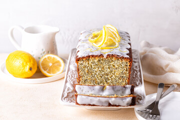 Poster - Homemade breakfast. Sliced pound cake with lemon zest, sugar and lemon glaze and poppy seeds on a white plate and white background.