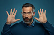 © Ivan - Confused male portrait. Gesture of refusal. It was not me. A meaningless emotion. Surprised expressive man raising his hands saying it's not me. On a blue empty background.generative ai