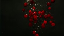 A slow-motion video of a large number of cranberries falling into the water. Berries seem to dance in their own mesmerizing dance. High quality 4k footage
