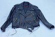 leather fashionable stylish black classic biker unbuttoned with iron zippers heavy old with iron fittings and rivets the jacket lies on the cold snow on the street during a winter day