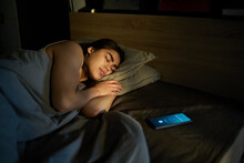 Woman Sleeping Near Alarm Ringing On Smart Phone At Home