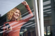 © Westend61 - Happy businesswoman holding smart phone seen through glass window
