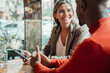 © Westend61 - Happy businesswoman looking at colleague sitting in cafe