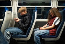 Boy And Girl Using Smart Phones Sitting In Train