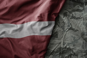 Wall Mural - waving flag of latvia on the old khaki texture background. military concept.