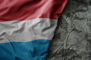 Wall Mural - waving flag of luxembourg on the old khaki texture background. military concept.