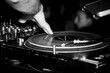 Schwarz-Weiß Aufnahme, Nahaufnahme von DJ-Hände, die einen Musiktisch in einem Nachtclub steuern.