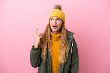 Wall Mural - Young blonde woman wearing winter jacket isolated on pink background thinking an idea pointing the finger up
