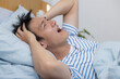 Asian man screaming madly on the blue bed Having a headache Because it is a disease related to pressure and migraine, to retirement age and health care concept.