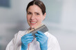dentist's assistant / female dentist with medical gloves holds/shows shade guide to check veneer of teeth