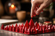 A hand carefully selects among miniature red paper houses arranged on a table, symbolizing real estate selection and investment.