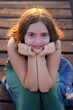 © Iryna - Summer portrait of young teenager girl is sitting on wooden bridge. Young tourist woman sits on the wooden bridge alone and enjoy the relaxation and freedom.
