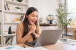 © NewSaetiew - Beautiful young woman using laptop while working in home office. Businesswoman happy and smiling at indoors.