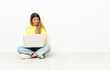 © luismolinero - Young woman with a laptop sitting on the floor with arms crossed and looking forward