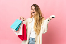Young Woman With Shopping Bag Isolated On Pink Background Holding Shopping Bags And A Credit Card
