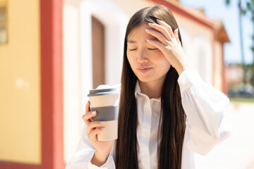 Wall Mural - Pretty Chinese woman at outdoors with headache and holding a take away coffee