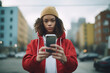 A teenage girl with curly hair and a red hoodie holds her phone in her hand, with a defiant and nonconformist look. No more Digital Harassment on social media
