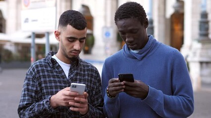 young black friends on the street  look at photos on their smartphone and laugh
