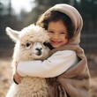 © olegganko - A beaming toddler cradles a fluffy and contented baby alpaca,