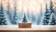 Small recycling paper gift box on the wood table with snowy winter trees in the backgroud with copy space