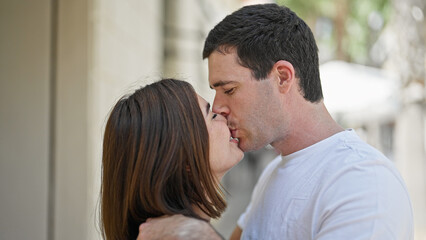 Beautiful couple standing together kissing at street