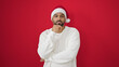 © Krakenimages.com - African american man standing with serious expression wearing christmas hat over isolated red background