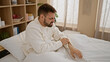 © Krakenimages.com - Young hispanic man scratching arm for itchy sitting on bed at bedroom