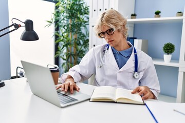 Sticker - Young blond man doctor using laptop reading book at clinic