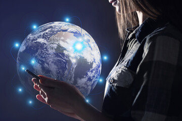 Wall Mural - global network. woman using smartphone on dark background, closeup. digital image of earth with conn