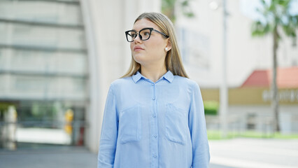 Wall Mural - Young blonde woman business worker standing with arms crossed gesture and serious expression at street