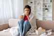 © Prostock-studio - Sick asian woman blowing her running nose in paper tissue at home