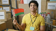 Young latin man volunteer holding belarus flag smiling at charity center