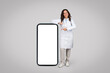 © Prostock-studio - Happy female doctor pointing at blank smartphone screen
