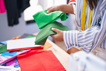 Sticker - Young beautiful hispanic woman tailor holding cloths at clothing factory